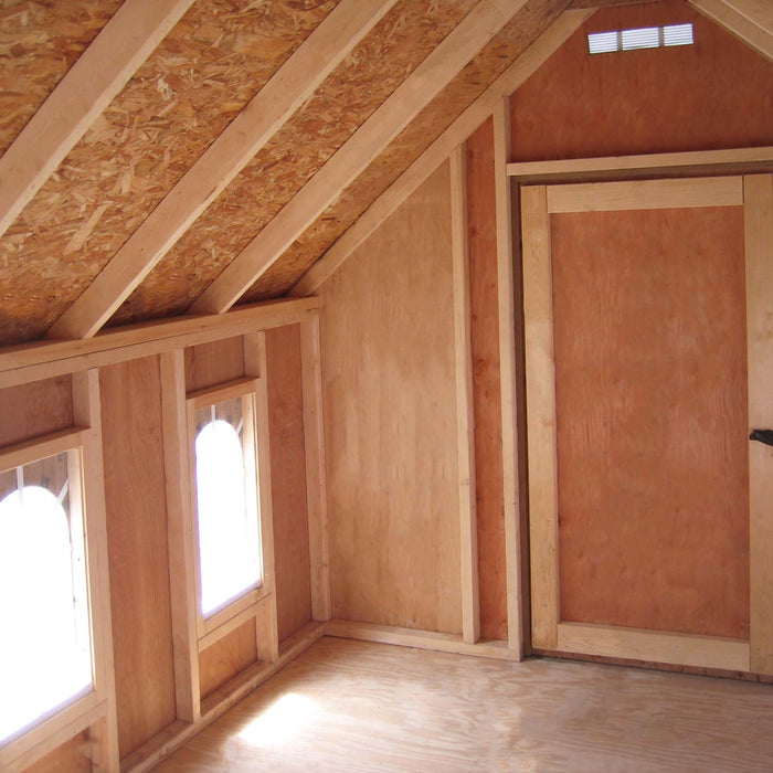 The cozy interior of the Little Cottage Company Stratford Schoolhouse Playhouse with the door open and sunlight streaming through the windows.