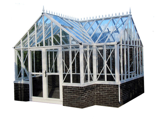  Full view of the Victorian greenhouse showcasing the entire structure with its white aluminum frame on a brick base, gable roof, and clear glass panels, against a clear sky backdrop.