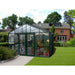 The Exaco Janssens Royal Victorian VI 46 Greenhouse in a residential setting with a lush lawn and neatly trimmed hedges, a perfect blend of functionality and home gardening.