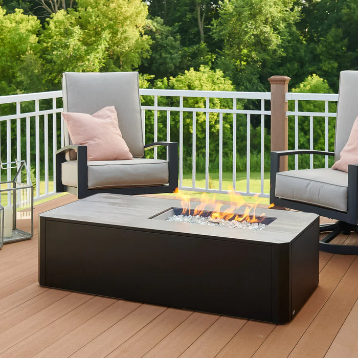 The Fire Pit Table lit with flames, with outdoor seating and decorative elements around it.