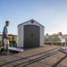 Children playing cornhole in front of the closed Lifetime 8 ft x 5 ft Outdoor Storage Shed on a deck.