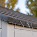 Close-up of rain droplets on the gutter of the Lifetime 8 ft x 7.5 ft Outdoor Storage Shed, with a focus on the shed's exterior textures against a blurred autumnal background.