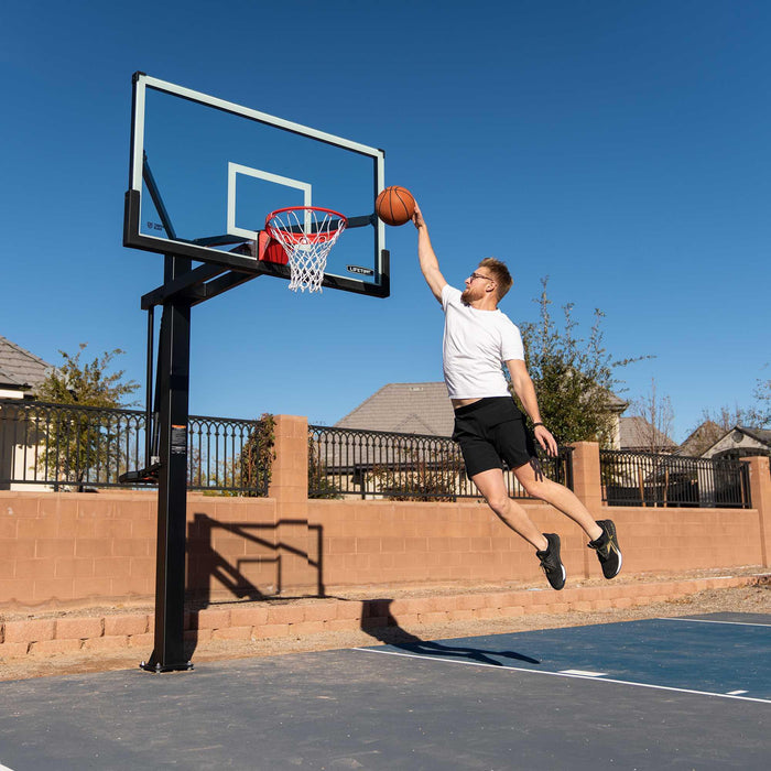 Action shot of a player making a jump shot at the Lifetime 72-Inch Mammoth Bolt Down Basketball Hoop on an outdoor court.