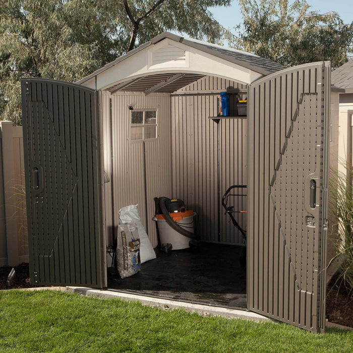 The Lifetime Outdoor Storage Shed open, revealing a lawn mower and gardening tools inside.
