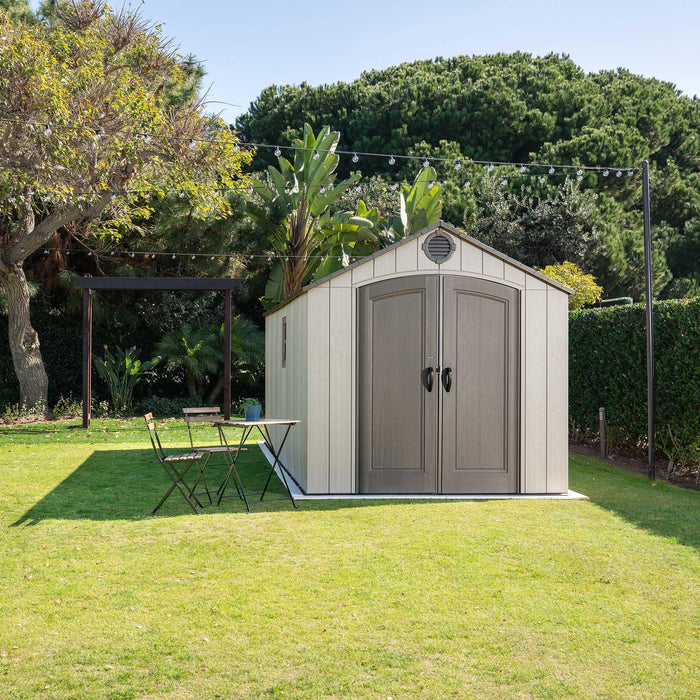 The Lifetime 8 x 17.5 ft Outdoor Storage Shed set up in a garden with outdoor furniture and greenery around.