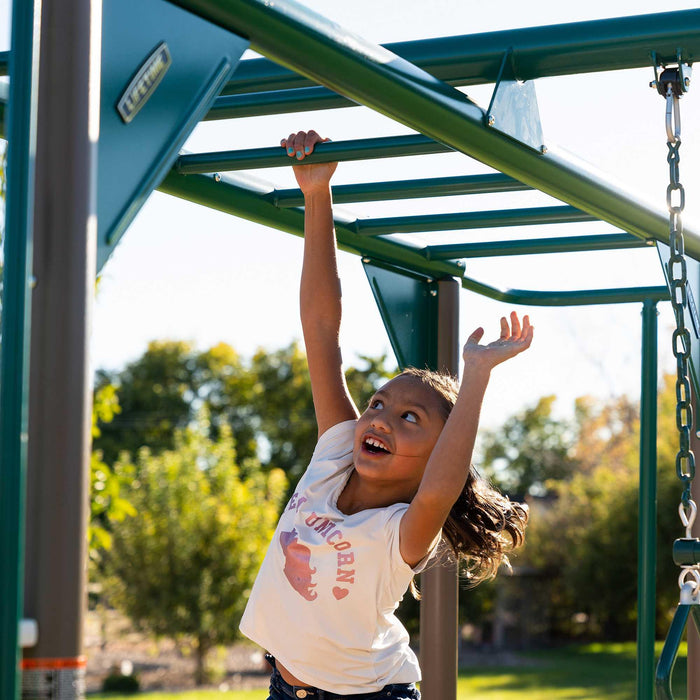 A child joyfully hanging from the monkey bars on the Lifetime 91080 Deluxe Playset.