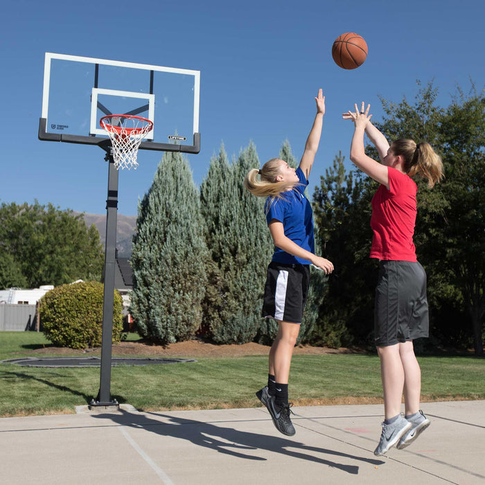 A woman shooting a basketball at the Lifetime Adjustable Bolt Down Hoop with another woman in defense.