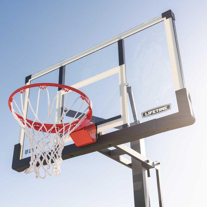 The Lifetime Adjustable Portable Basketball Hoop with a 54-Inch Tempered Glass backboard bathed in sunlight.