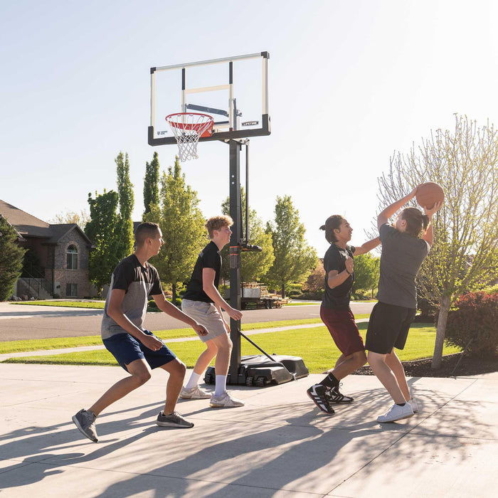 Players engaging in a basketball game with the Lifetime Adjustable Portable Basketball Hoop on a residential street.