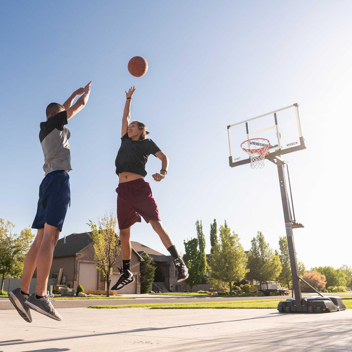 Two players jumping to score in a game of basketball with the Lifetime Adjustable Portable Basketball Hoop in the foreground.
