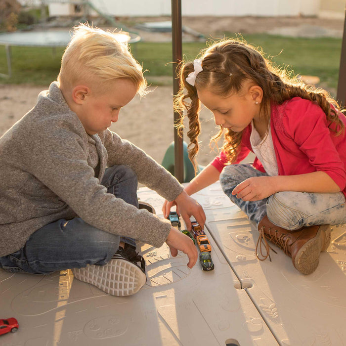 Two children playing with toy cars on the activity map of the Lifetime Adventure Clubhouse Playset.