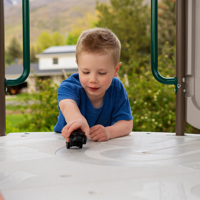 A child playing with a toy car on the game platform of the Lifetime Adventure Slide Tower.