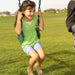 A young girl in a green shirt smiling while sitting on a swing at the playset.