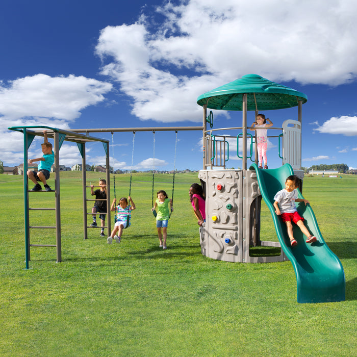 A wide view of the playset with multiple children playing on swings and slides.