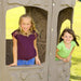 Two girls smiling through the window frames of the Lifetime Adventure Tower Deluxe playset.