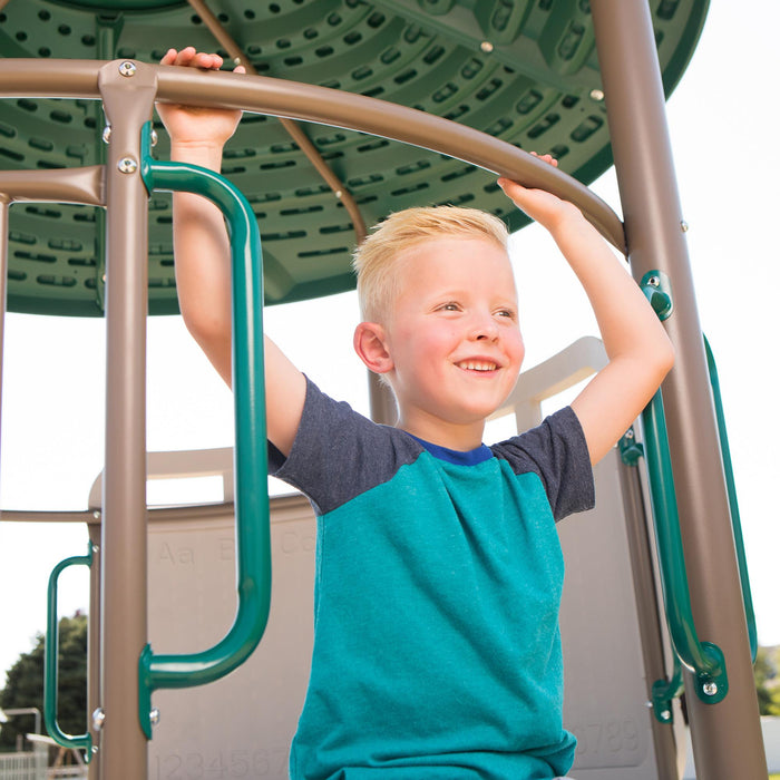 A boy at the top of the Lifetime Adventure Tower Playset with a joyful expression, in a sunny outdoor setting.