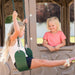 A young girl conversing with another child who is swinging at the Lifetime Adventure Tower Playset.