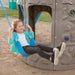 A child smiling while sitting on a blue swing attached to the Lifetime Adventure Tower Playset.