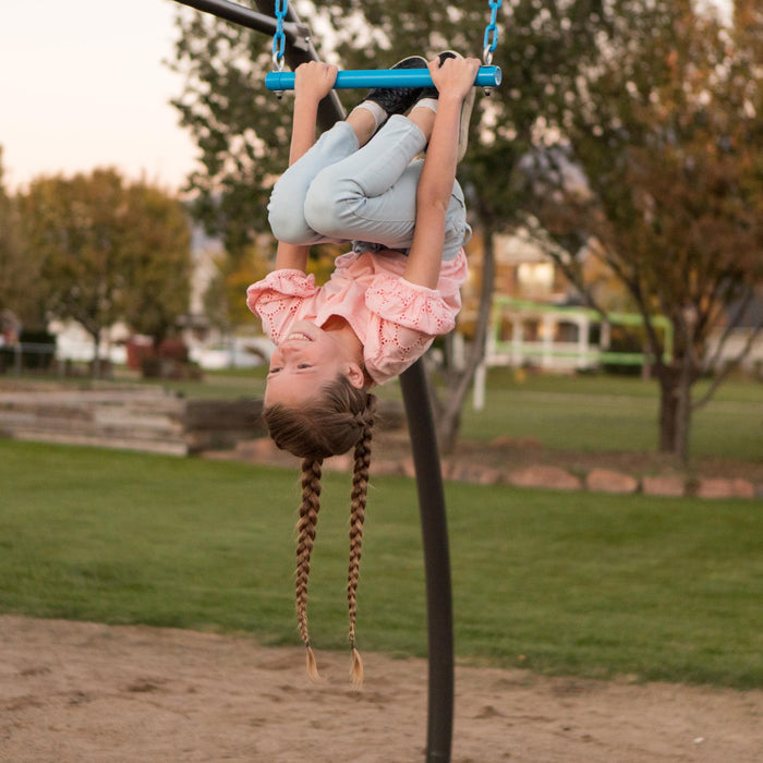 A child hanging upside down from a blue swing on the Lifetime Adventure Tower Playset with a playful expression.