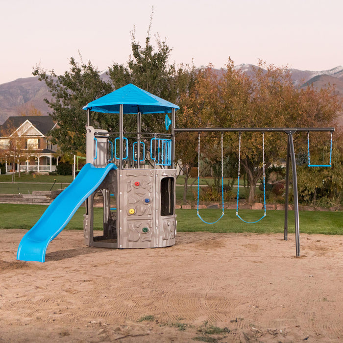 Full view of the Lifetime Adventure Tower Playset with slide and swings, installed in a sandy area at dusk.
