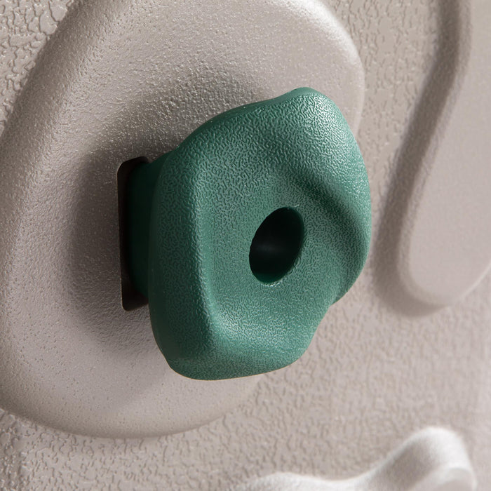 Detailed view of a single green rock climbing grip on the gray surface of the Lifetime Adventure Tower Playset.