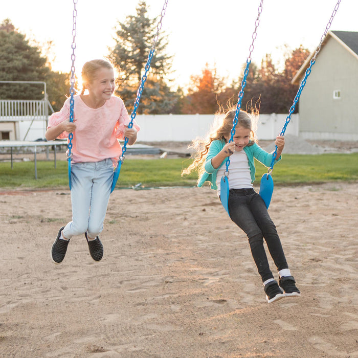 Two girls joyfully swinging on the blue swings of the Lifetime Adventure Tower Playset in the evening.