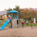 Children playing on the Lifetime Adventure Tower Playset featuring a blue slide and swings in an outdoor setting.