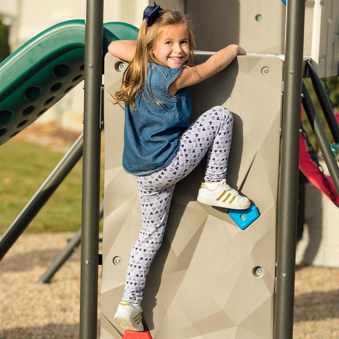  A young girl climbing the rock wall of the Lifetime Adventure Tunnel Playset with a slide in the background.