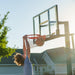 A player dunking a basketball on the Lifetime Crank Adjust Bolt Down Basketball Hoop with a 54-inch backboard in an outdoor residential setting.