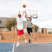 Action shot of a jump shot play with two players at the Lifetime Mammoth Basketball Hoop in a backyard setting.