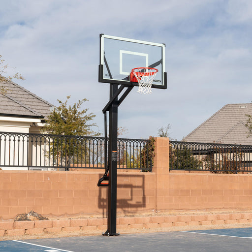 Lifetime Mammoth Bolt Down Basketball Hoop installed outdoors, with clear sky and residential background.