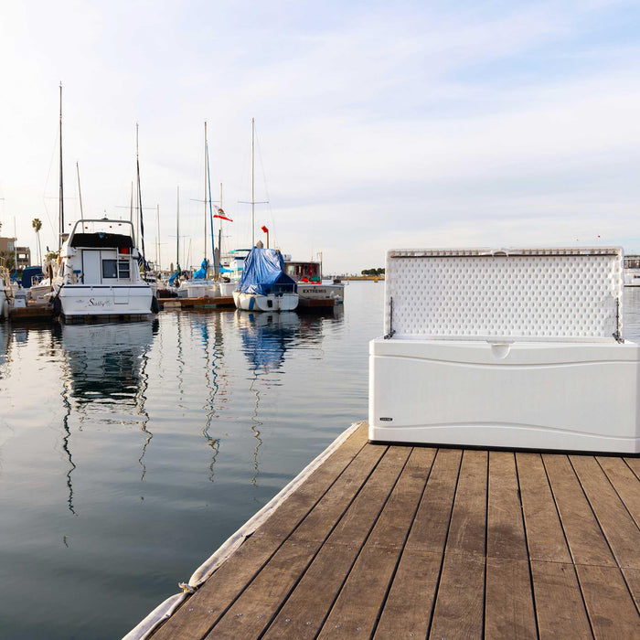 White Lifetime Marine Dock Box, model 60348, open and placed on a wooden dock with marina and boats in the background.