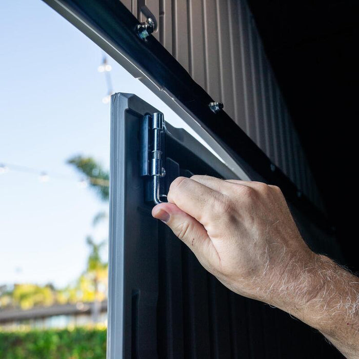 Detailed image of a person's hand securing the door latch on the Lifetime 8 ft x 12.5 ft Outdoor Storage Shed, emphasizing the hardware quality.