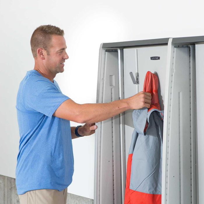 Man hanging a red bag inside the grey Lifetime storage locker.
