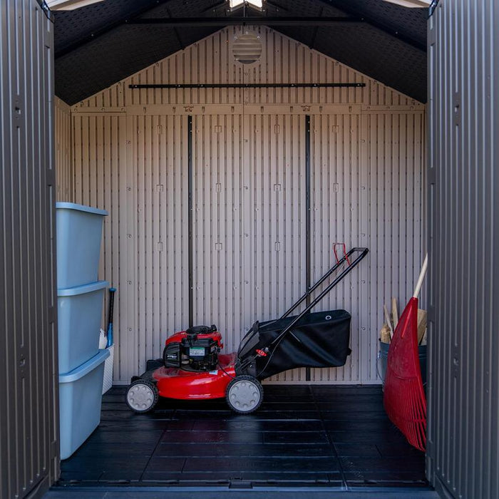 Interior view of the Lifetime 8 ft x 5 ft Outdoor Storage Shed storing a lawnmower, storage bins, and garden tools.