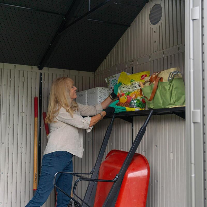 Woman reaching for gardening supplies on the shelving inside the Lifetime 10 x 8 ft. Outdoor Storage Shed.