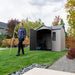 Person standing with a rake outside the open Lifetime 10 x 8 ft. Outdoor Storage Shed.