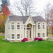Little Cottage Company's Grand Mansion playhouse with a portico front, set against a natural landscape.