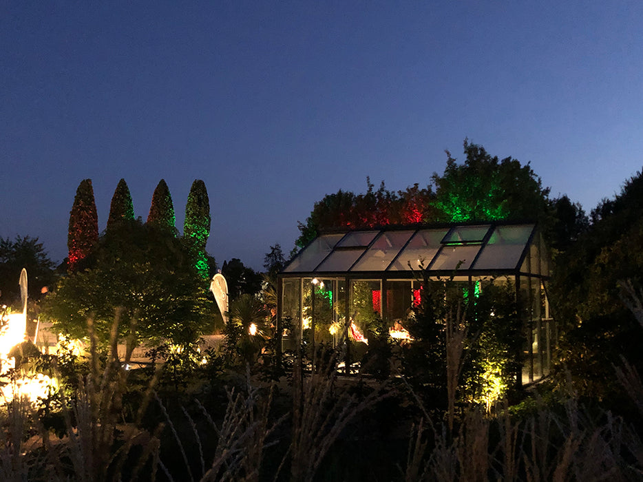 A nighttime scene of the Livingten Greenhouse illuminated from within