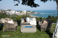 A scenic patio with outdoor seating and the Elementi Plus Lucerne Square Concrete Fire Pit Table, offering a view of the ocean.