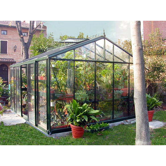 Luxuriant garden setting with a large Exaco Janssens Royal Victorian VI 46 Greenhouse, showcasing its sturdy structure and transparency revealing lush interior vegetation.