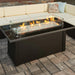 A detailed view of the Fire Pit Table's glass flame guard and the warm glow of the fire.