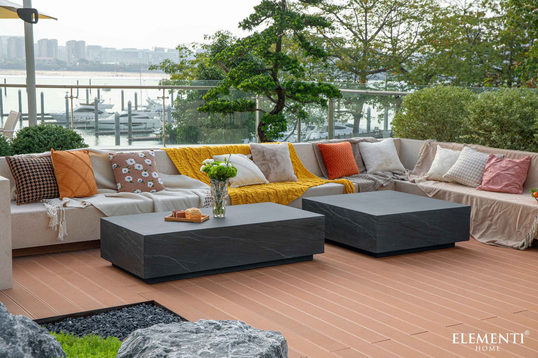 Elementi Colorado Series rectangle coffee table in slate black featured in an outdoor seating area with colorful cushions and a marina backdrop.