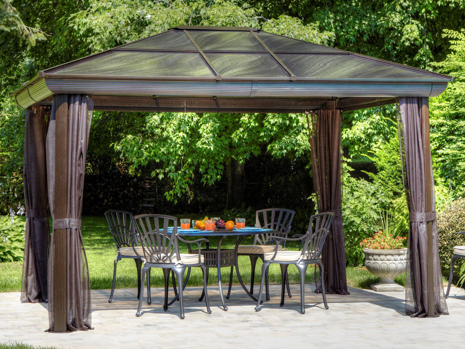 A full setup of the 10x12 Venus Gazebo, showcasing the polycarbonate roof, privacy curtains drawn open, and outdoor furniture inside.