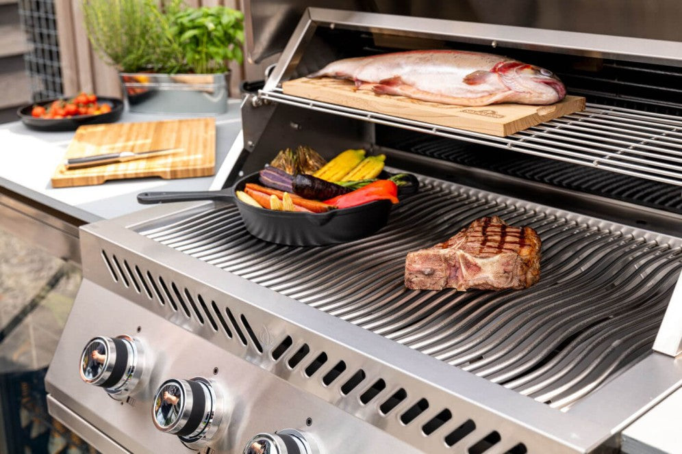 The Napoleon Grills Built-In 500 Series 32-Inch 4-Burner Gas Grill Head in use, with various foods being grilled, highlighting the grill's capacity and surface.