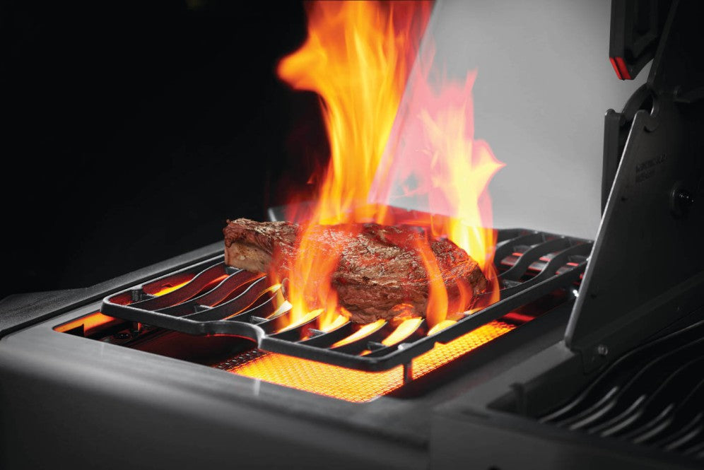 Close-up of the high-intensity Sizzle Zone™ side burner on the Napoleon Grills Prestige® 500 RSIB Grill with a steak flaming on the grill.