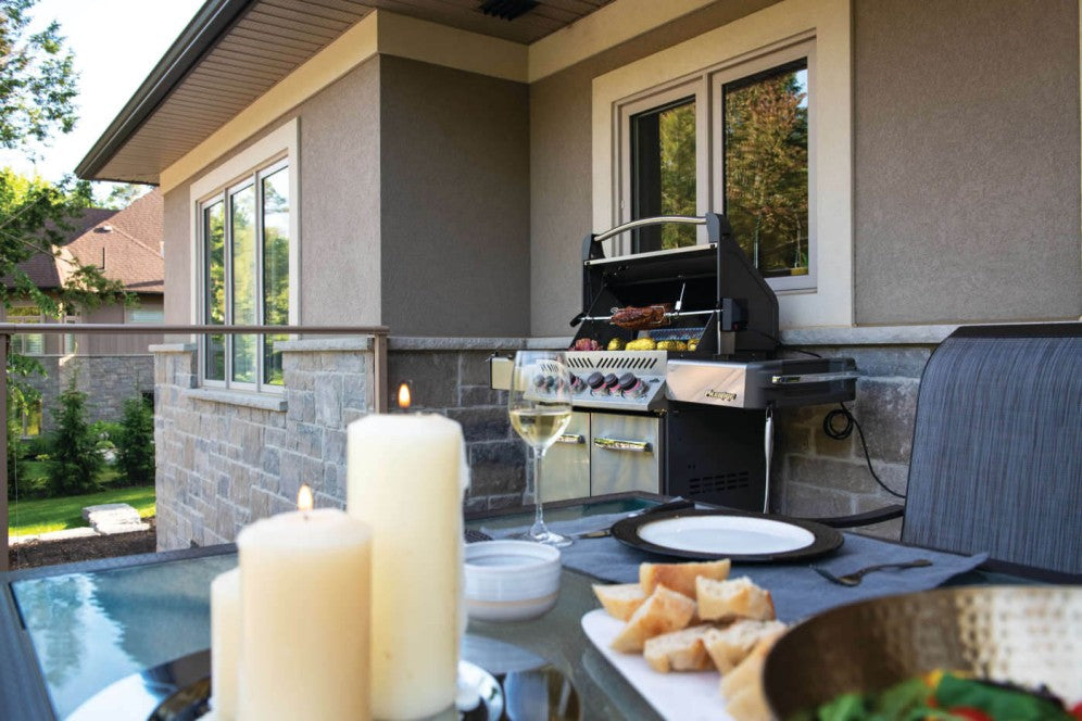 Napoleon Grills Prestige® 500 RSIB 6-Burner Grill in stainless steel placed on a home patio with lit candles and a dining setup in the foreground.