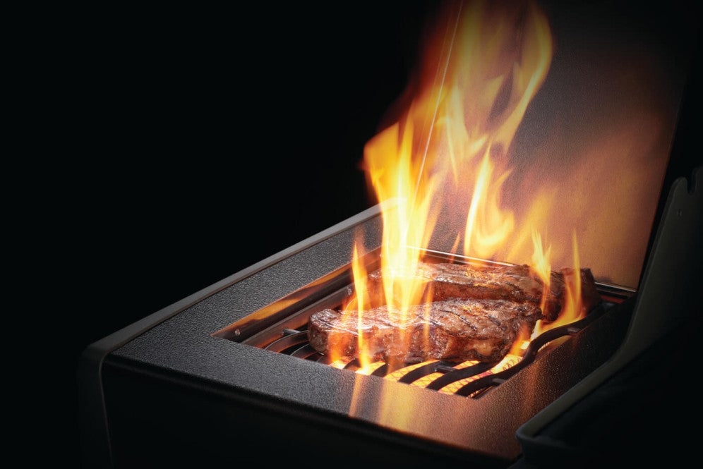 The Napoleon Grills Rogue XT 625 SIB Grill's infrared side burner in use, with a flame grilling a steak, emphasizing the grill's cooking capabilities.