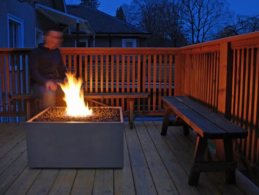 An atmospheric evening view of a lit Solus Decor Firebox 30 on a deck, creating a warm and inviting outdoor space.