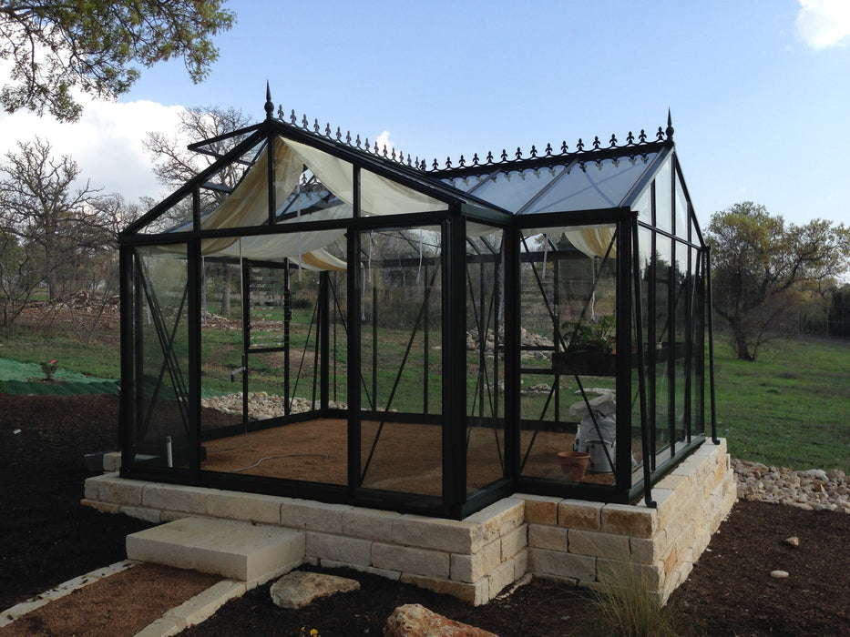 Luxurious estate greenhouse with a Victorian Orangerie style by Exaco Janssens, surrounded by natural stone steps and lush vegetation.